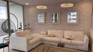 A modern living room with a white sectional sofa, a glass coffee table, and three framed pictures on the wall. - Luxury suite 16th floor of the best building in Quito (Quito)