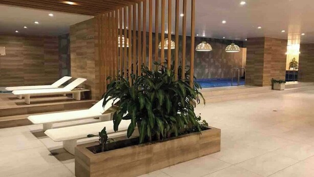 A modern indoor area with a reception desk, lounge chairs, and a large planter with green plants. - Luxury suite 16th floor of the best building in Quito (Quito)