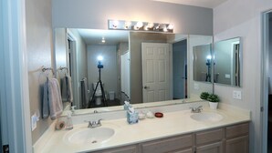 Une salle de bain avec deux lavabos, un grand miroir et un meuble-lavabo avec des tiroirs.