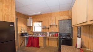 A compact kitchen with wooden cabinets, a refrigerator, a stove, and a microwave.