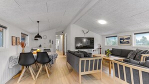 Ett modernt vardagsrum med en soffa, ett matbord och en tv.