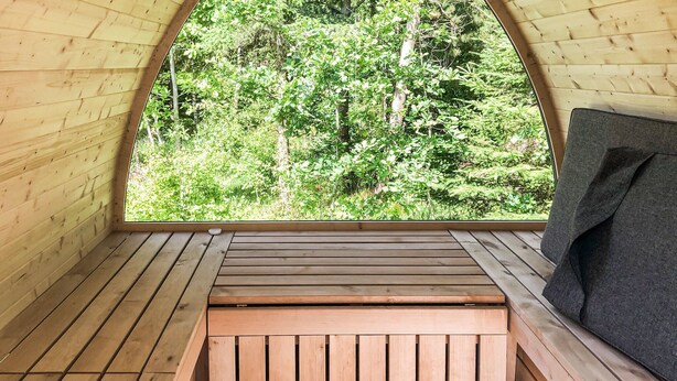 En inredning med träpaneler och utsikt över en skog genom ett stort fönster.