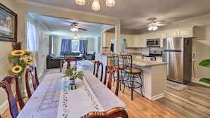 A modern kitchen with a central island, stainless steel appliances, and a dining area with a long table and chairs. - Convenient Jacksonville Home w/ Yard & Patio! (Jacksonville)