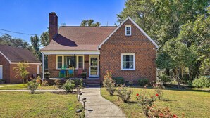 A single-story brick house with a front porch, a chimney, and a small garden with a pathway leading to the entrance. - Convenient Jacksonville Home w/ Yard & Patio! (Jacksonville)