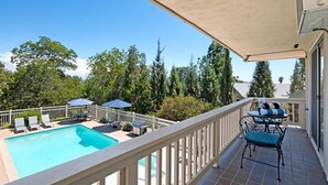 Ett område vid poolen med en pool, solstolar, parasoller och en möblerad sittplats under tak.