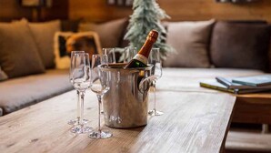 A wooden table with a champagne bottle and glasses in a metal bucket.