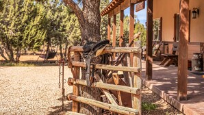 A rustic wooden structure with a metal gate, a tree, and a building in the background.