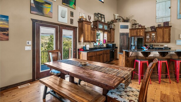 A spacious kitchen with wooden cabinets, a large island, and red bar stools.