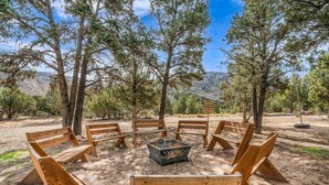 A campsite with wooden benches arranged in a circle around a central fire pit.