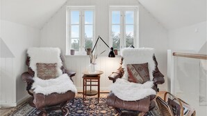 Un cuarto ático acogedor con dos sillones de cuero, una mesita y una lámpara.