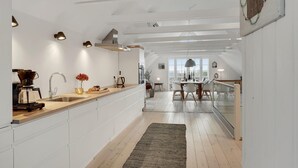 Una cocina moderna con armarios blancos, encimera de madera y una cafetera.