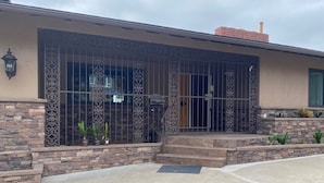 A house with a stone facade, large windows with metal bars, and a brick chimney.