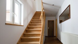 A wooden staircase leading to a door, white walls, and a window.
