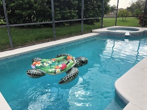 Relax by the pool, surrounded by lush greenery and a clear view of the water.