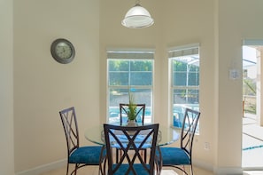 Enjoy meals in this dining area with a round table, two chairs, and a potted plant.