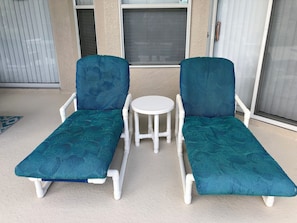 Relax in a tranquil outdoor space with two lounge chairs and a table.