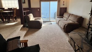 A living room with a fireplace, a sofa, a coffee table, and a dining area with chairs and a table. - Roomy three bedroom home with Boat/RV parking (Coulee Dam)