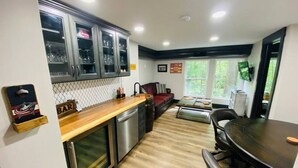 A modern kitchen with a wooden countertop, stainless steel appliances, and a dining area with a round table. - Fully Renovated Cabin in Hocking Hills - Hot Tub, Game Room, Wifi, Fireplace (Amanda)