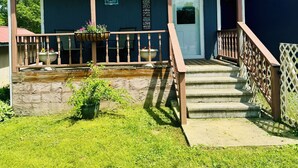 A two-story building with a covered porch, a front door, and a staircase leading to the entrance.