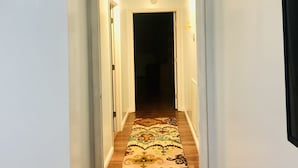 A hallway with a welcome sign, wooden flooring, and a patterned rug.