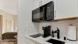 A modern kitchen with a built-in microwave, coffee maker, and sink. - La Dolce Vita Studio (Port St. Lucie)