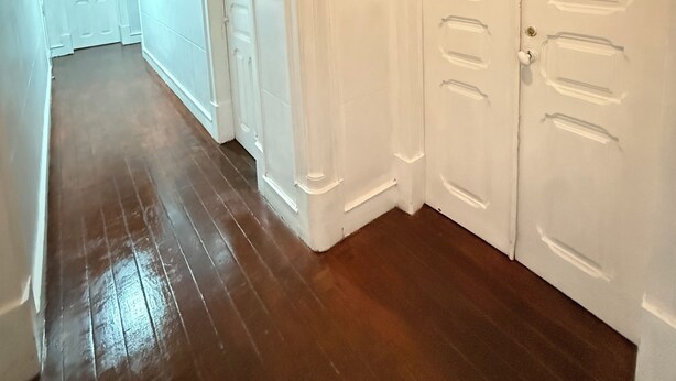 Un pasillo con suelo de madera, paredes blancas y puertas con los números 1 y 4.