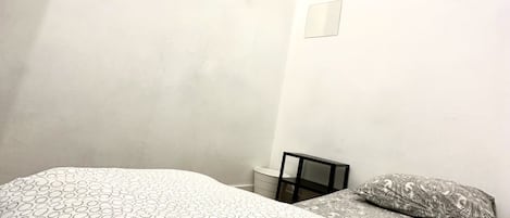 Un dormitorio con cama, una mesita y una ventana.
