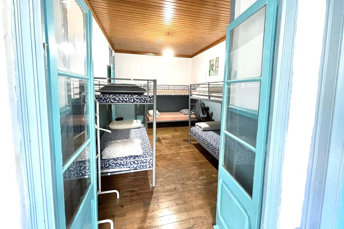 A dormitory room with bunk beds, wooden flooring, and a wooden ceiling.