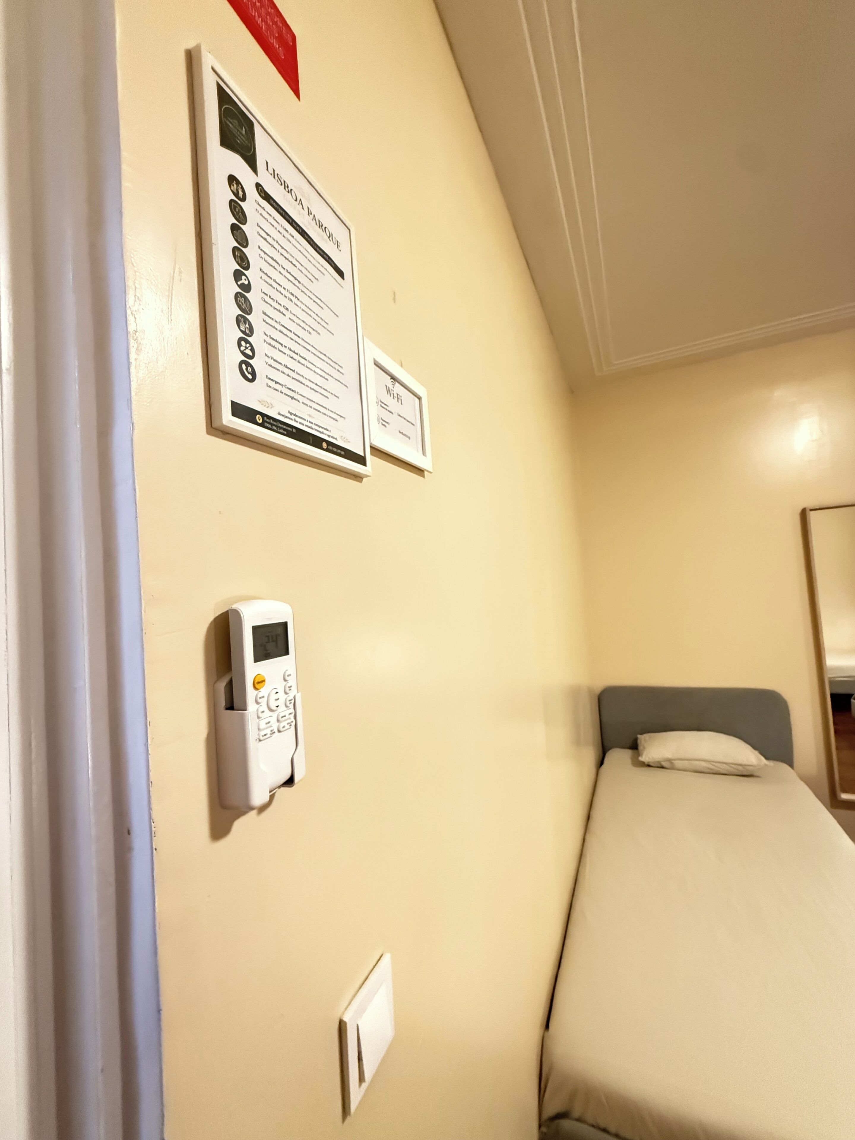 Een hotelkamer met een bed, een bediend thermostat, een Wi-Fi symbool en een lijst met informatie in een lijstwerk.