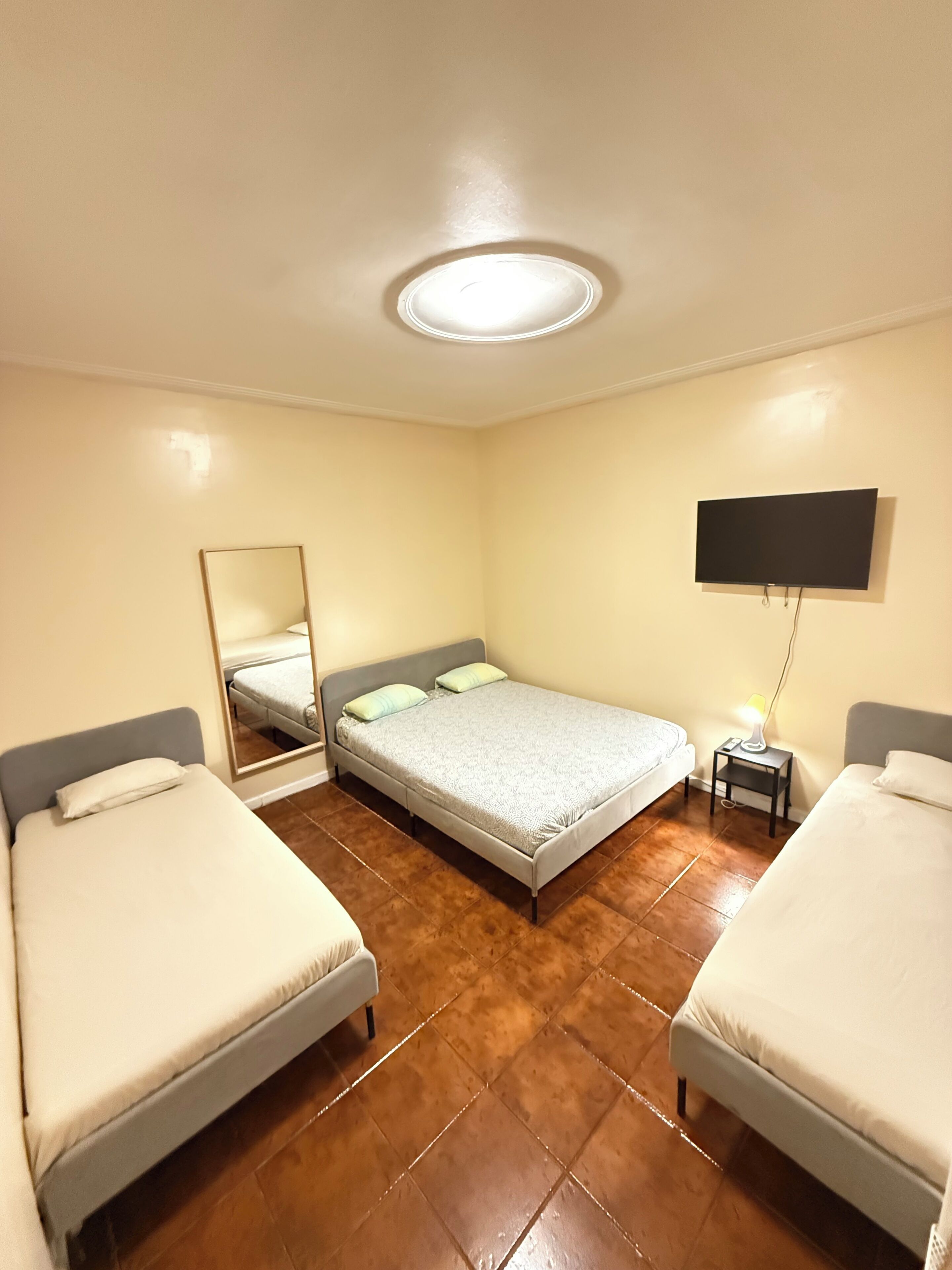 Een hotelkamer met twee bedden, een flatscreen televisie, een spiegel en een plafondlamp.