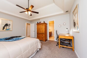 Ein Schlafzimmer mit einem Bett, einem Schreibtisch, einem Kleiderschrank und einem Deckenventilator.