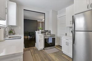 Una cocina moderna con armarios blancos, electrodomésticos de acero inoxidable y piso de madera.