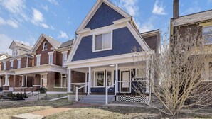 A two-story house with a blue roof, white trim, and a front porch with a railing. - Gatsby vibes house in Old Oaks, close to everything (Columbus)