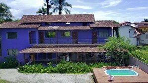 A two-story building with a tiled roof and a swimming pool in the foreground. - Pousada Tropicália Paraty (Paraty)