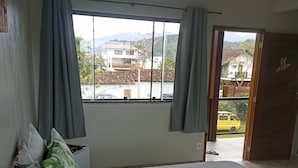 A bedroom with a bed, curtains, a window, and a view of the outside. - Pousada Tropicália Paraty (Paraty)