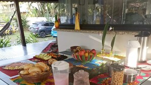 A breakfast table with various food items and a pitcher of pink beverage. - Pousada Tropicália Paraty (Paraty)