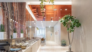 A modern hotel lobby with a marble reception desk, a large potted plant, and a long corridor leading to the elevators. - Kwangsu Hotel (Busan)