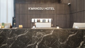 A reception desk at Kwangsu Hotel with a marble top and a dark wood panel wall behind it. - Kwangsu Hotel (Busan)