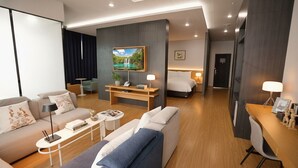 A modern hotel room with a living area, a bed, a desk, and a TV. - Kwangsu Hotel (Busan)