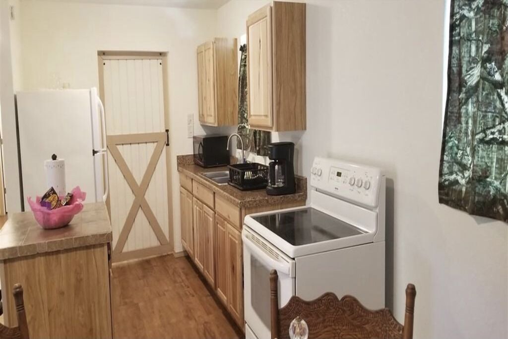 Una cocina compacta con armarios de madera, estufa blanca, microondas y cafetera.