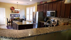 A kitchen with granite countertops, stainless steel appliances, and dark wooden cabinets. - Spanish Villa with heated pool, hot tub and outdoor living space (Phoenix)