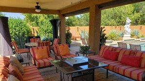 An outdoor patio area with striped sofas, a glass-top coffee table, and a ceiling fan. - Spanish Villa with heated pool, hot tub and outdoor living space (Phoenix)