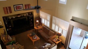 A living room with a sofa, armchairs, a coffee table, a TV, and a ceiling fan. - Spanish Villa with heated pool, hot tub and outdoor living space (Phoenix)