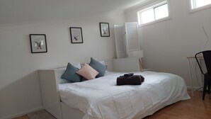 A bedroom with a bed, pillows, a bedside table, a chair, and a window. - Townhouse close to shelly beach Port Macquarie (Port Macquarie)
