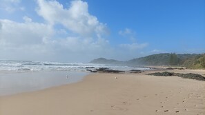 A sandy beach with waves, rocky outcrops, and a distant mountain. - Townhouse close to shelly beach Port Macquarie (Port Macquarie)