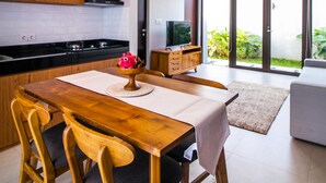 A modern kitchen with wooden cabinets, a black countertop, and a dining table with chairs. - De Hsahe Villa (Tabanan)