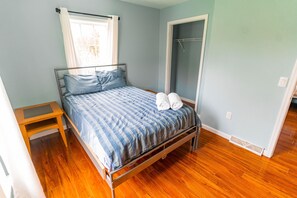 Une chambre à coucher avec un lit, un plancher en bois et une fenêtre avec des rideaux.