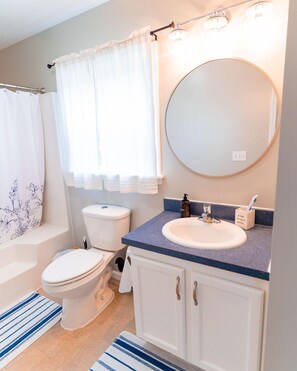 Une salle de bain équipée d’une baignoire, de toilettes, d’un lavabo et d’un miroir.