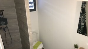 Ein Badezimmer mit Dusche, Toilette, Waschbecken und einer kleinen Topfpflanze.