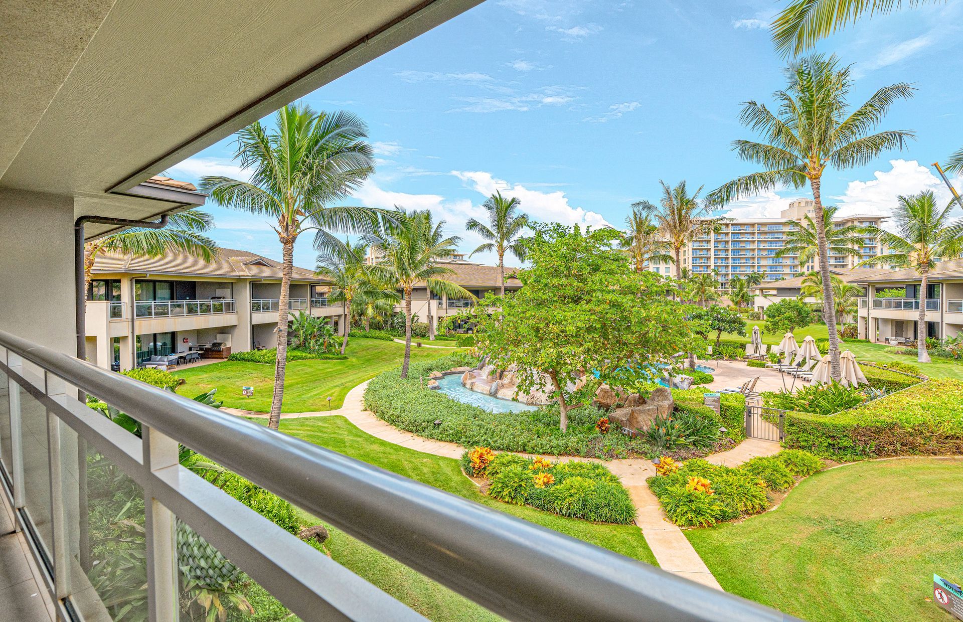 Um resort com piscina, palmeiras e um edifício com várias varandas.